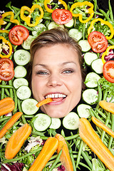 Image showing Cute blond girl shot in studio with vegetables aroound the head