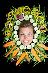 Image showing Cute blond girl shot in studio with vegetables aroound the head