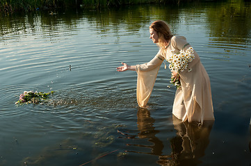 Image showing Attractive woman lowers wreath in water