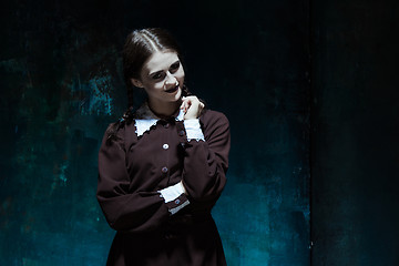 Image showing Portrait of a young smiling girl in school uniform as killer woman