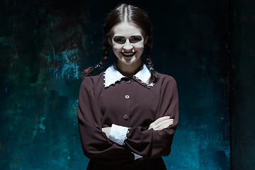 Image showing Portrait of a young smiling girl in school uniform as killer woman