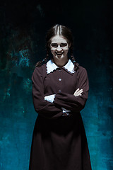 Image showing Portrait of a young smiling girl in school uniform as killer woman