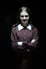 Image showing Portrait of a young smiling girl in school uniform as killer woman