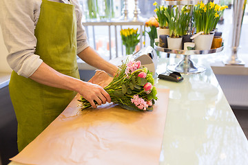 Image showing florist wrapping flowers in paper at flower shop