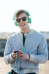 Image showing happy young man in headphones with smartphone