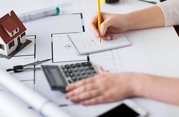 Image showing close up of hand on blueprint writing to notebook