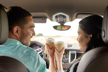 Image showing happy man and woman driving in car with coffee