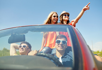 Image showing happy friends driving in cabriolet car at country