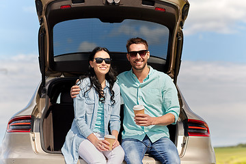 Image showing happy couple with coffee at hatchback car trunk