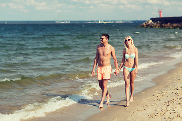 Image showing happy couple in swimwear walking on summer beach