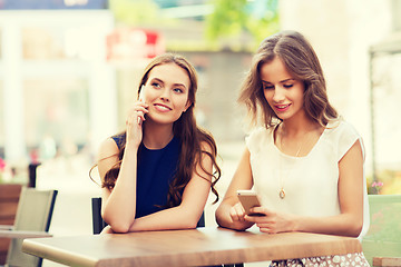 Image showing happy young women with smartphones at outdoor cafe