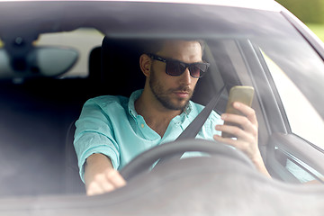 Image showing man in sunglasses driving car with smartphone