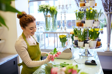 Image showing smiling florist woman making bunch at flower shop