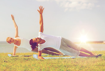 Image showing smiling couple making yoga exercises outdoors