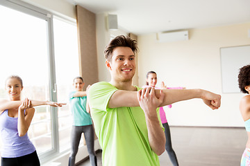 Image showing group of smiling people stretching in gym