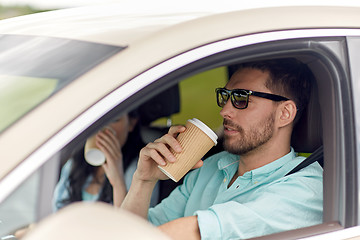 Image showing happy man and woman driving in car with coffee