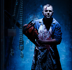 Image showing Bloody Halloween theme: crazy killer as butcher with electric saw