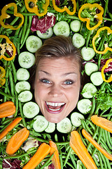 Image showing Cute blond girl shot in studio with vegetables aroound the head