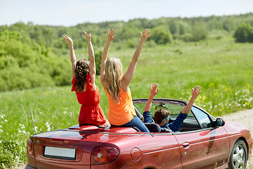 Image showing happy friends driving in cabriolet car at country