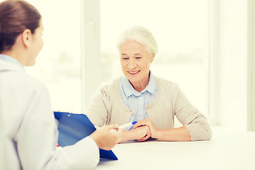 Image showing doctor with clipboard and senior woman at hospital