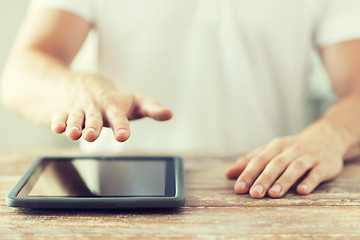 Image showing close up of male hands with tablet pc on table