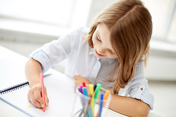 Image showing happy girl drawing with felt-tip pen in notebook