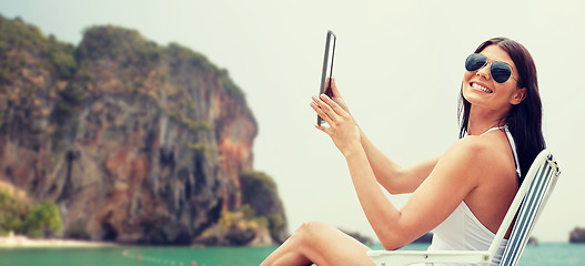 Image showing smiling woman with tablet pc sunbathing on beach