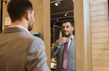 Image showing man trying tie on at mirror in clothing store