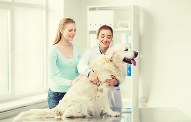 Image showing happy woman with dog and doctor at vet clinic