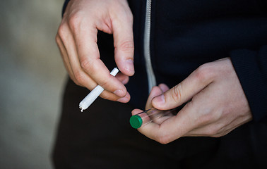 Image showing close up of addict hands with marijuana joint tube