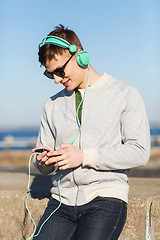 Image showing happy young man in headphones with smartphone