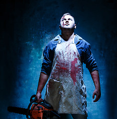 Image showing Bloody Halloween theme: crazy killer as butcher with electric saw