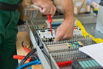 Image showing Electrician assembling industrial electric cabinet.