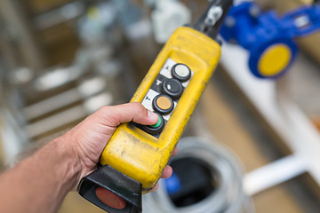 Image showing Industrial worker pushing on button of machinery controler.