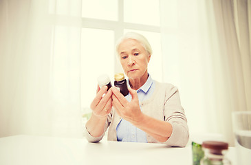 Image showing senior woman with medicine jars at home