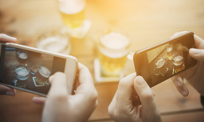 Image showing close up of hands with smartphone picturing beer