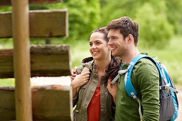 Image showing smiling couple at signpost with backpacks hiking