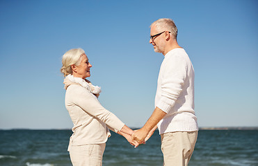 Image showing happy senior couple holding hands summer beach