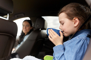 Image showing little girl driving in car and drinking from cup