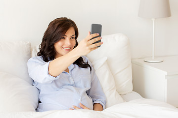 Image showing pregnant woman taking smartphone selfie at home