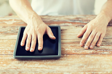 Image showing close up of male hands with tablet pc on table