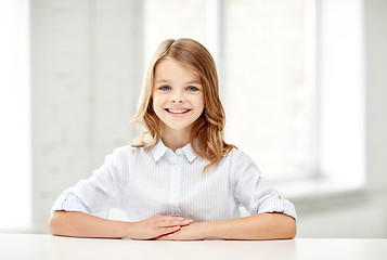 Image showing happy smiling school girl sitting at table