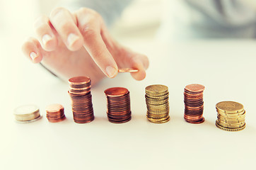 Image showing close up of female hand putting coins into columns