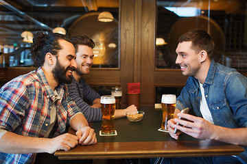 Image showing male friends with smartphone drinking beer at bar