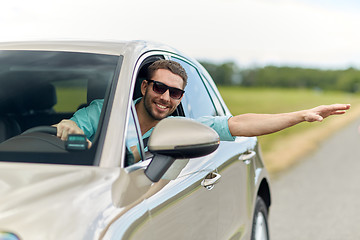 Image showing happy man in shades driving car and waving hand