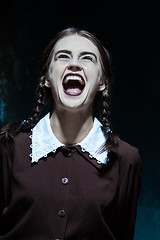 Image showing Portrait of a young smiling girl in school uniform as killer woman