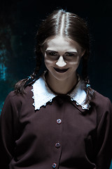 Image showing Portrait of a young smiling girl in school uniform as killer woman