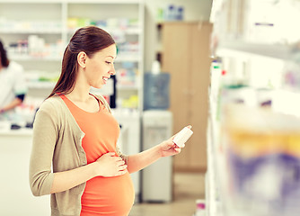 Image showing happy pregnant woman with medication at pharmacy