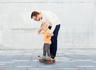 Image showing happy father and little son on skateboard