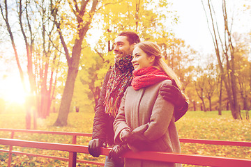 Image showing smiling couple hugging on bridge in autumn park